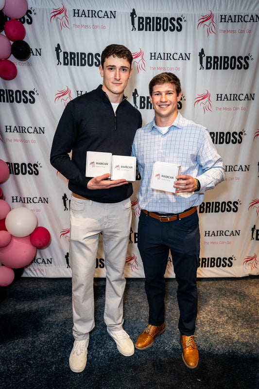 Two men holding awards in front of a Briboss and Haircan branded backdrop. 5